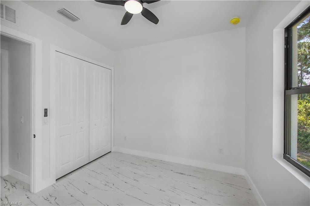 White walls with a black-framed window and a black ceiling fan