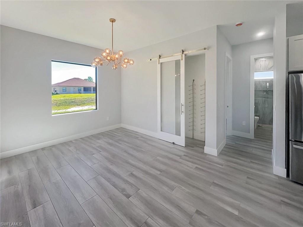 Light-toned wood-finish flooring, contemporary chandelier, and a large window