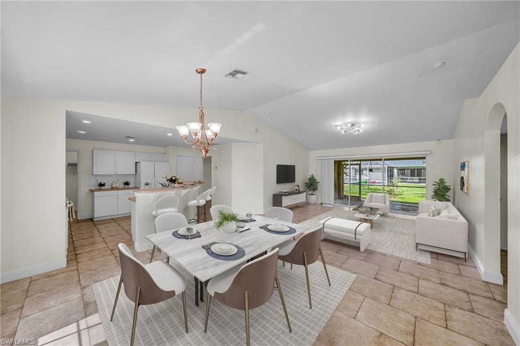 Vaulted ceilings, a full kitchen with white cabinetry, a kitchen island with seating, tiled flooring, and a screened-in patio