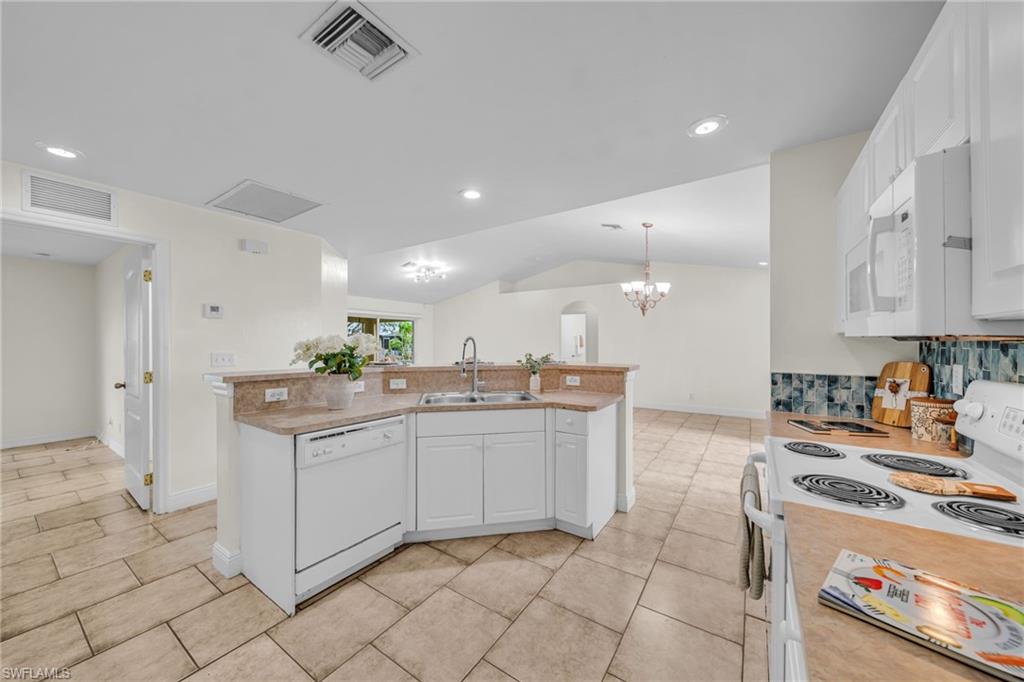 Kitchen featuring a built-in dishwasher, white cabinetry, a dual basin sink, and a tile backsplash