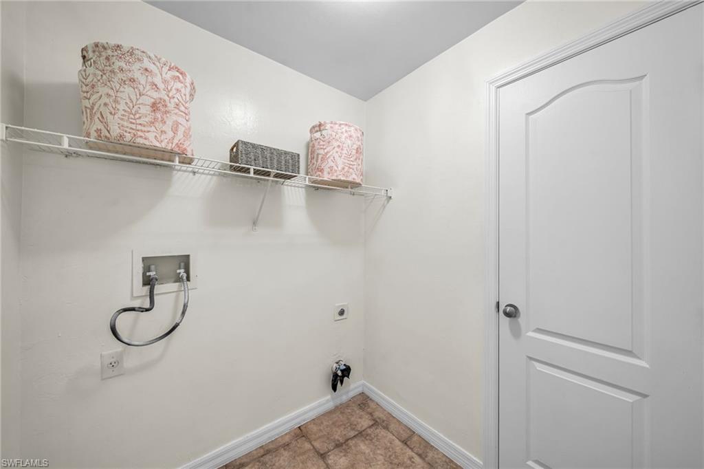 Utility area with a wire shelf, tile flooring, and a paneled door