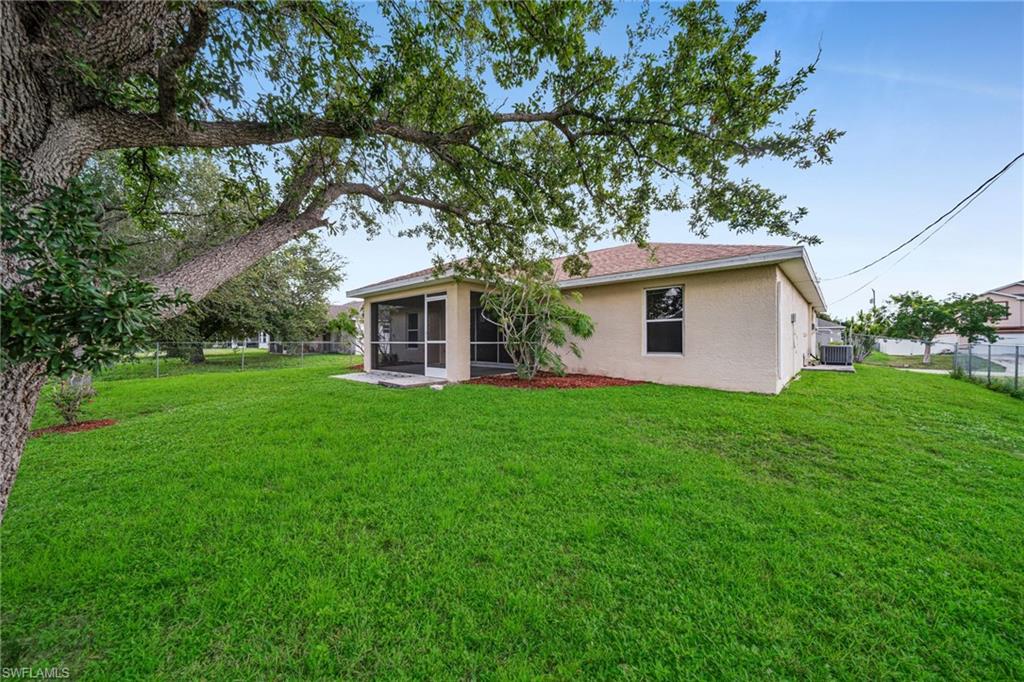 Expansive backyard with a manicured lawn, mature tree, and a screened-in patio