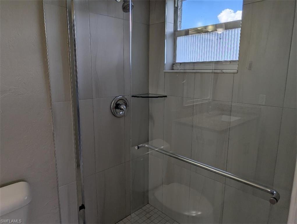 Bathroom featuring a stall shower and a textured wall