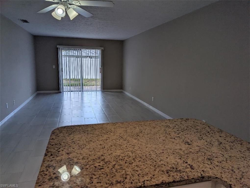 Unfurnished room with a ceiling fan, light tile patterned floors, and a textured ceiling