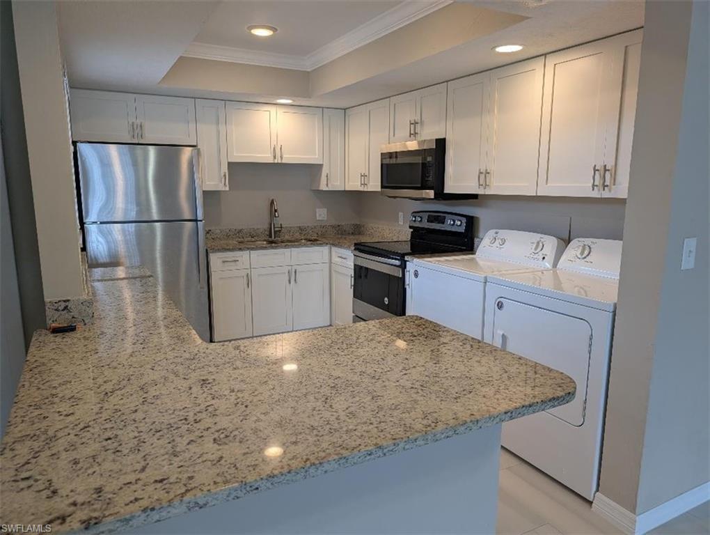 Kitchen featuring ornamental molding, white cabinets, stainless steel appliances, a peninsula, and light stone countertops