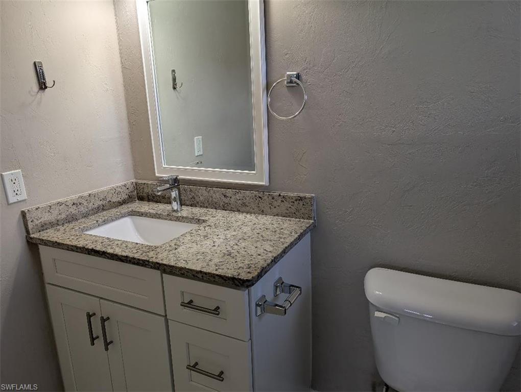 Half bathroom featuring a textured wall and vanity
