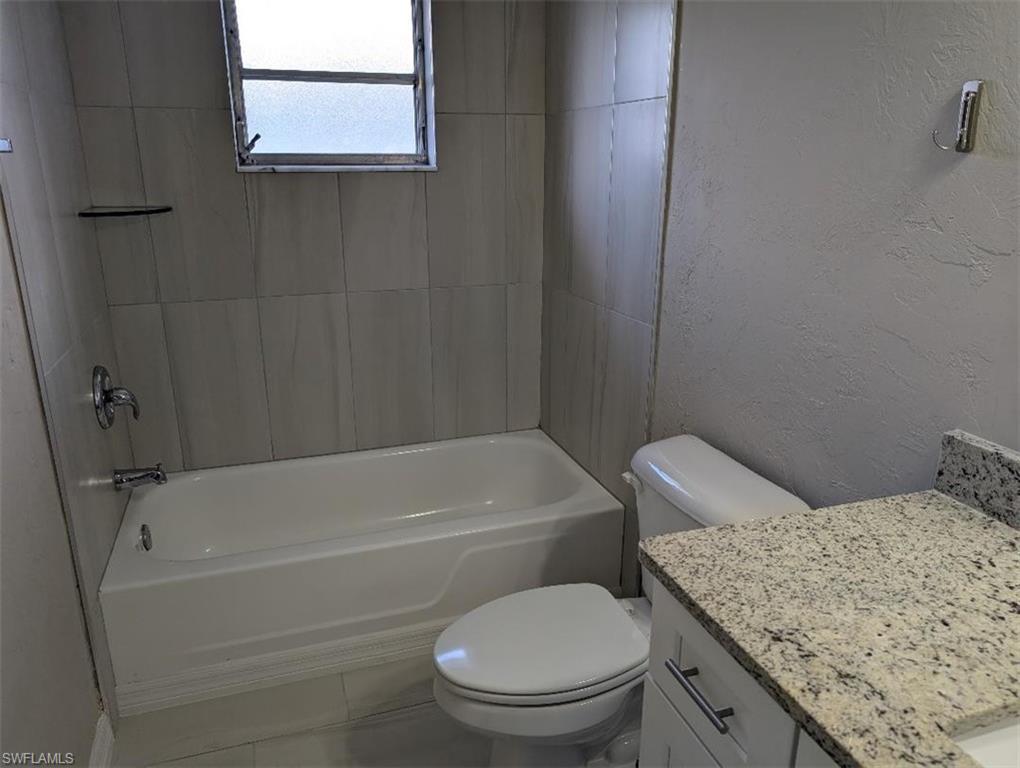 Full bath featuring a textured wall, vanity, and tub / shower combination