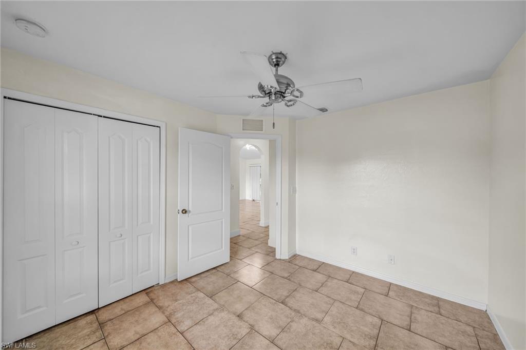 Neutral-toned tile flooring, ceiling fan, white paneled bifold closet doors, and a white interior door