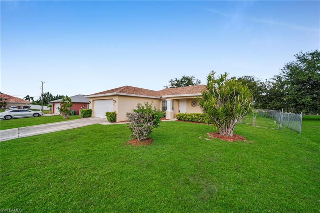 Single-story residence featuring a stucco exterior, attached garage, concrete driveway, and front lawn landscaping