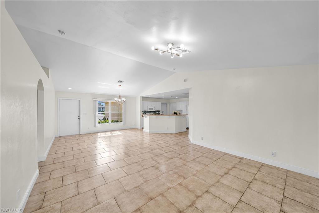 Vaulted ceilings, tile flooring, window with exterior view, arched doorway, and built-in kitchen peninsula