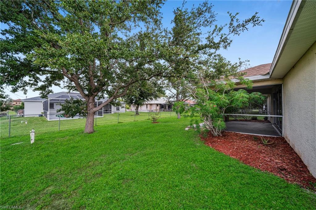 Expansive lawn with mature trees and a screened patio