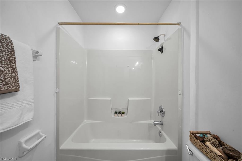 Bathtub and shower combination with white surround, chrome fixtures, and recessed lighting