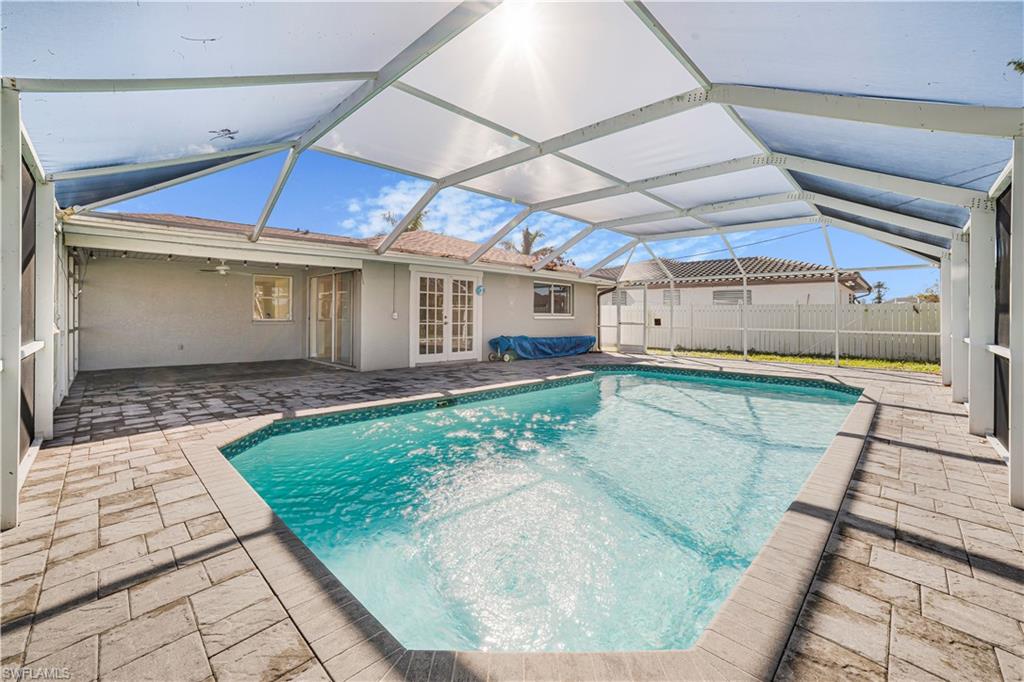 View of pool featuring glass enclosure, a patio area, french doors, and ceiling fan