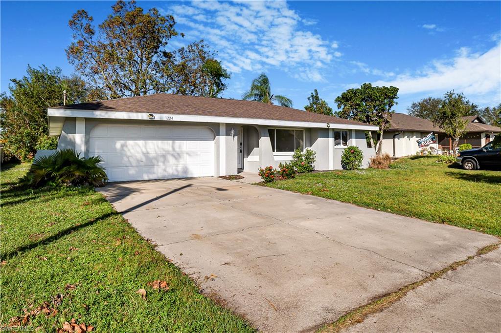 Single story home with a garage and a front yard