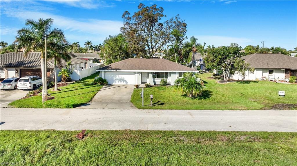 Single story home with a garage and a front lawn