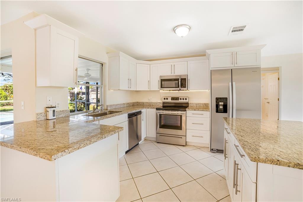 Kitchen featuring light stone counters, white cabinetry, appliances with stainless steel finishes, sink, and kitchen peninsula