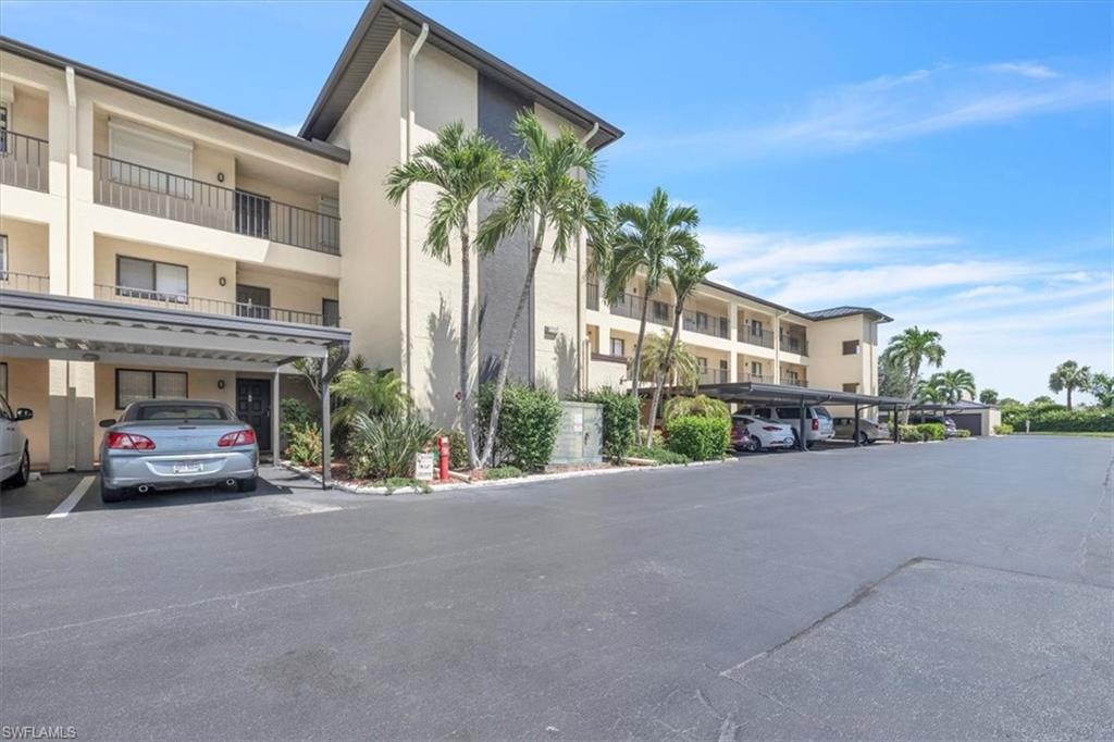 Multi-story building featuring covered parking, private balconies, and surrounding tropical landscaping