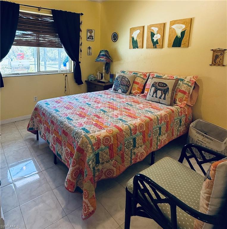 Neutral-toned tile flooring, light yellow painted walls, and a window with wood-finish blinds