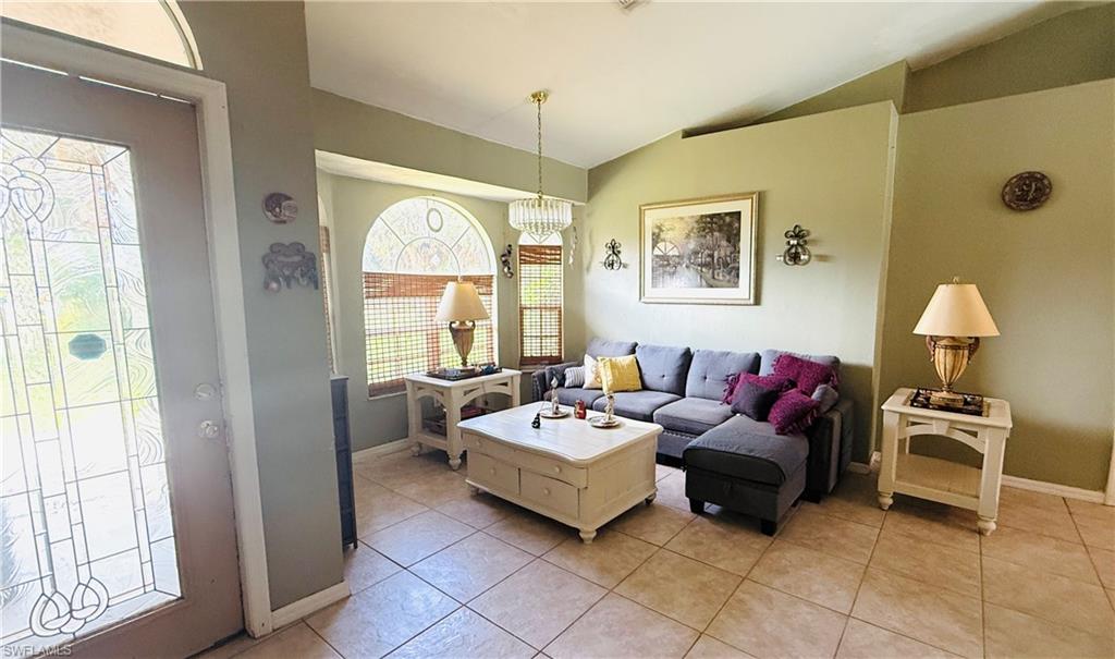 Living area featuring tile flooring, vaulted ceilings, and a decorative stained-glass entry door