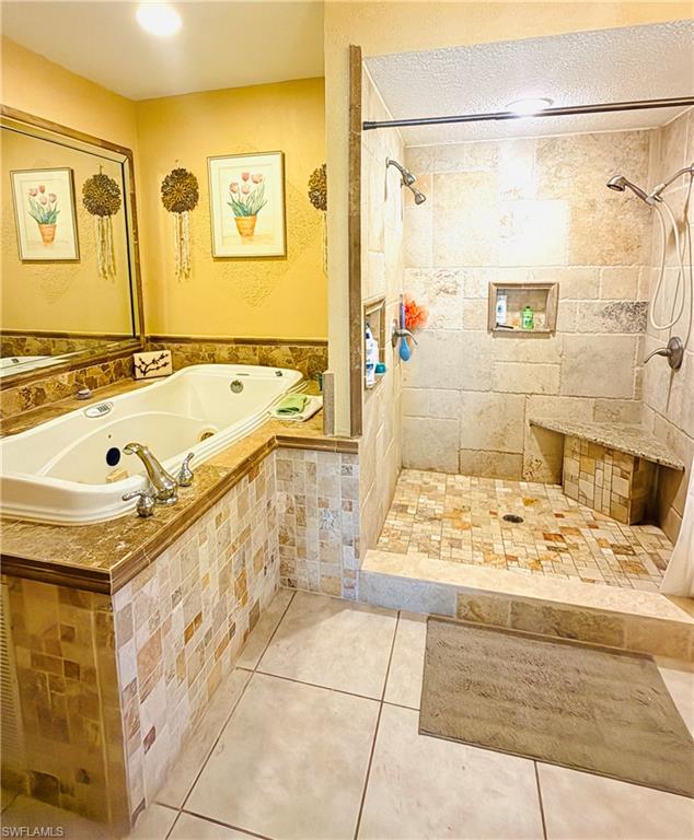 Soaking tub with a tiled surround, a separate shower with a built-in bench, and dual shower heads