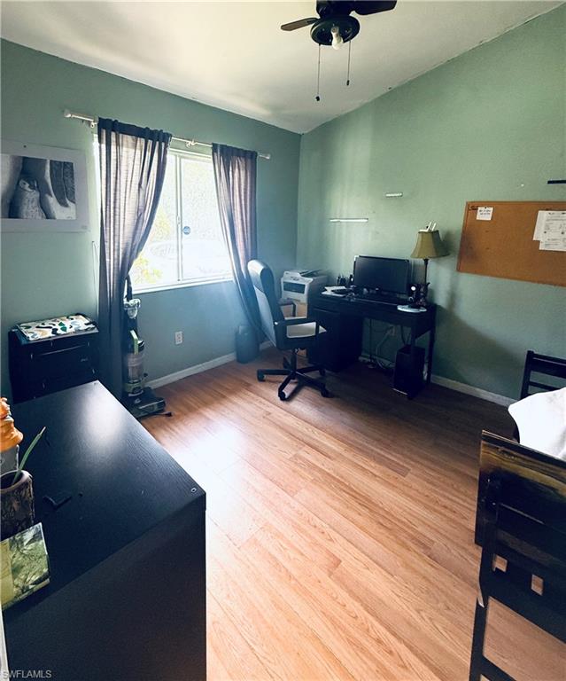 Wood-finish flooring, a window with natural light, and a ceiling fan