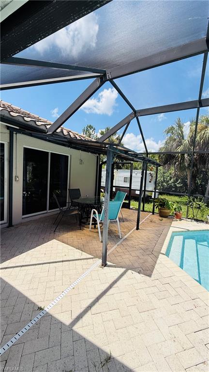 Screened enclosure featuring a swimming pool, a paver patio, and sliding glass doors