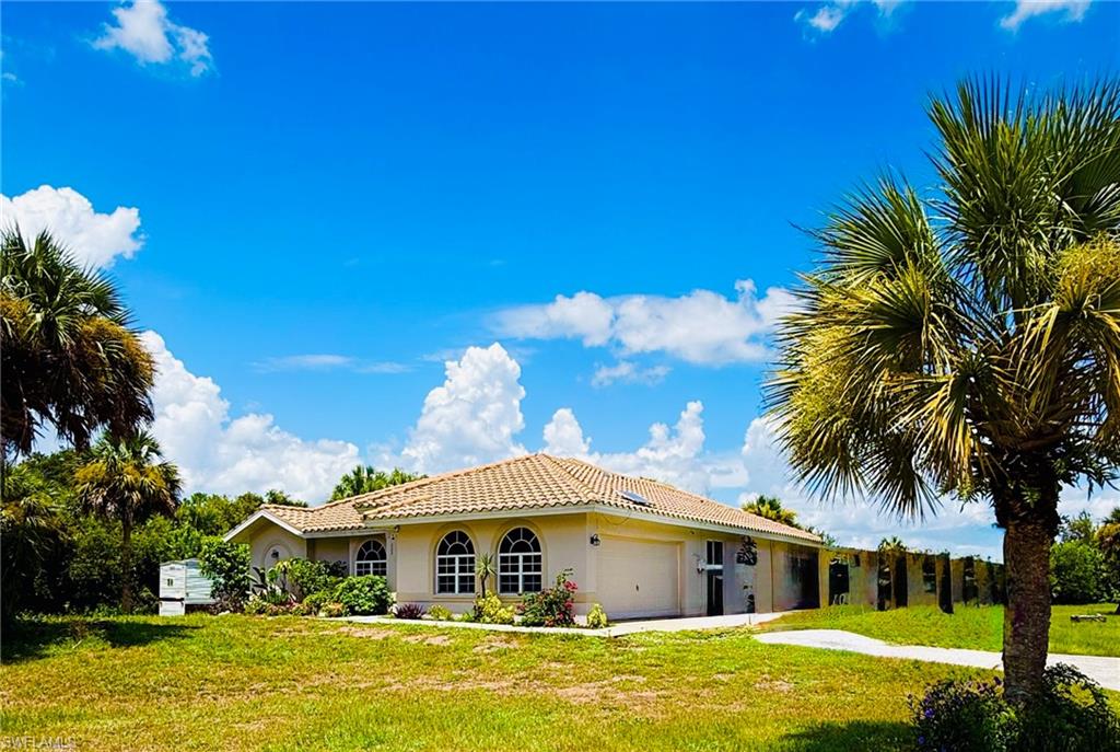 Cream stucco exterior with a tile roof, featuring arched windows and an attached garage