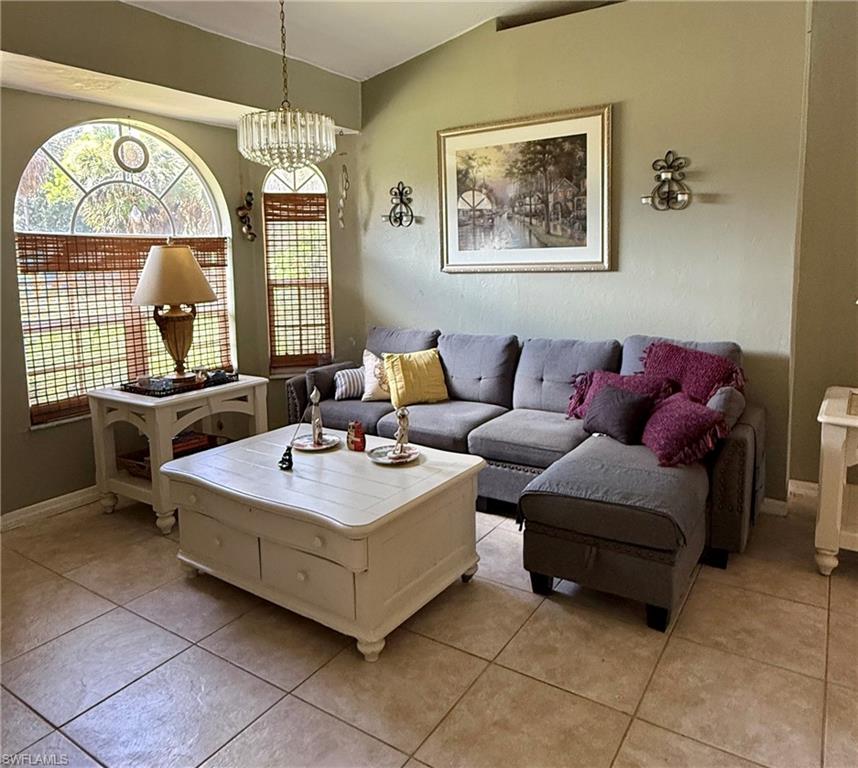 Vaulted ceiling, arched window, tiled flooring, and a crystal chandelier