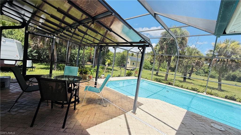 Screened swimming pool with a brick paver deck and a covered patio area