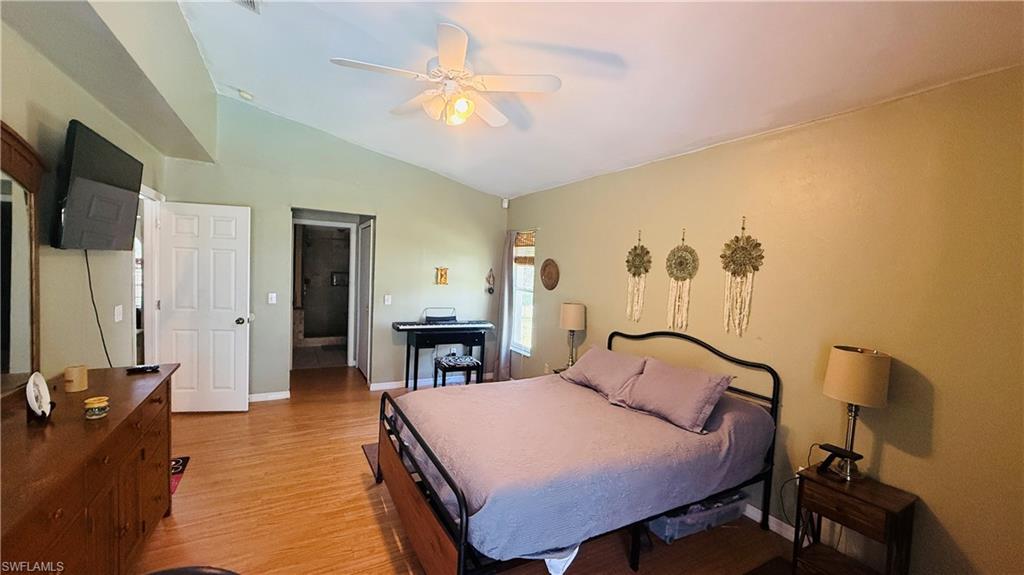 Vaulted ceilings with a ceiling fan, wood-finish flooring, and a paneled door
