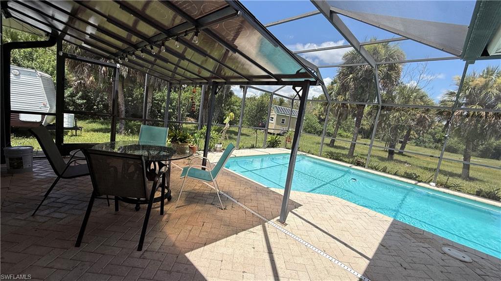 Screened patio with a covered section, brick paver flooring, and an in-ground swimming pool