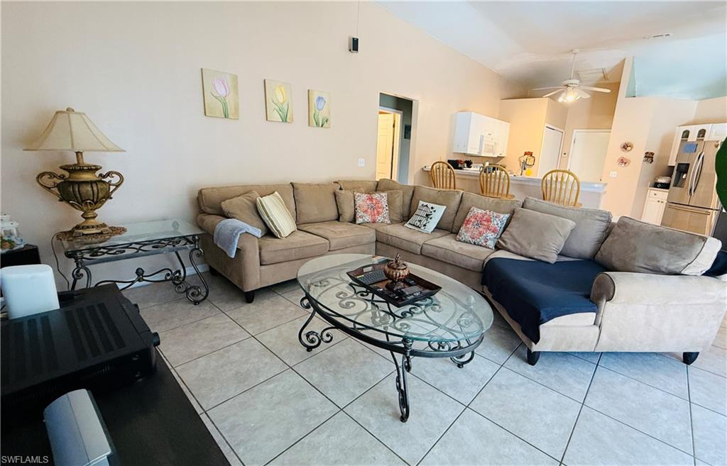 Vaulted ceiling with an installed ceiling fan, tiled flooring, built-in kitchen cabinetry, and stainless steel kitchen appliances