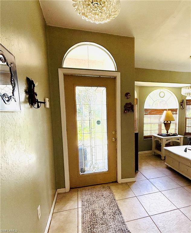 Entryway featuring a decorative glass door with an arched transom window, tiled flooring, and a decorative ceiling light fixture