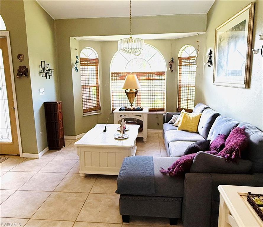 Bay window with arched architectural detailing, tile flooring, and a crystal chandelier