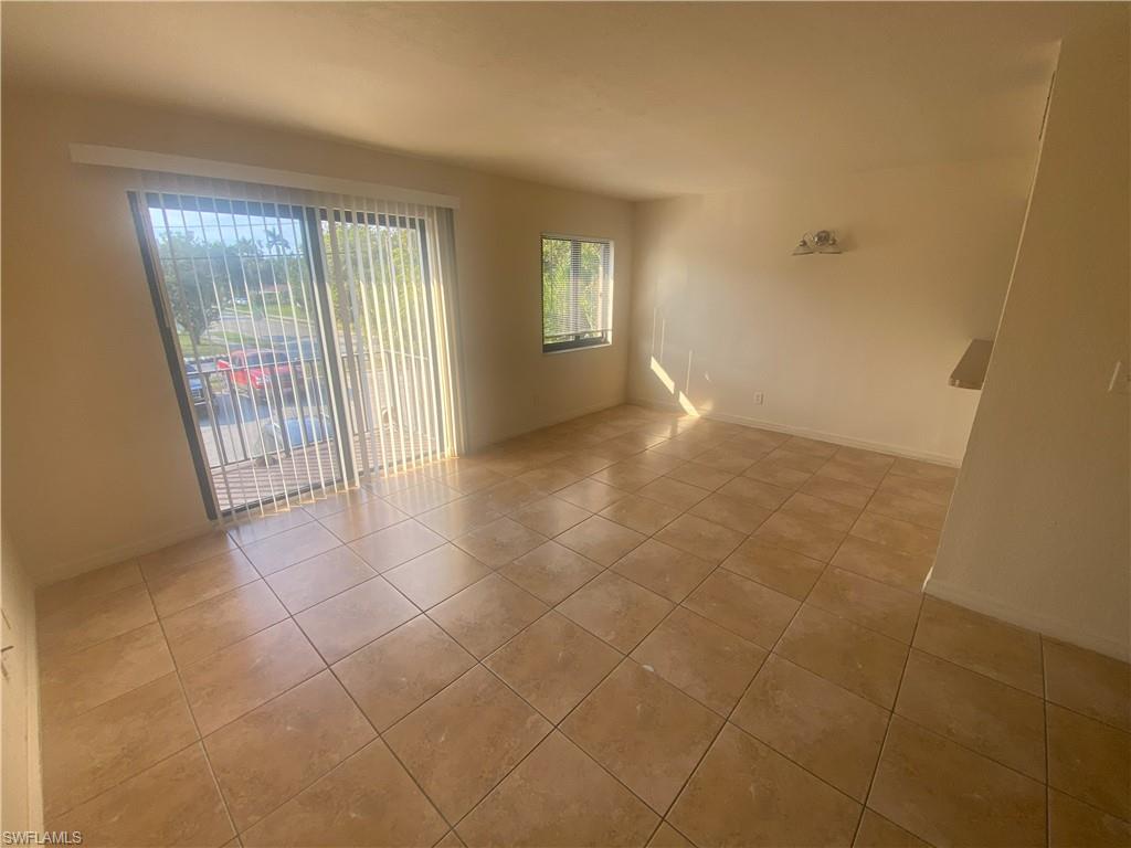 Expansive tile flooring, sliding glass door with vertical blinds, and a built-in wall shelf