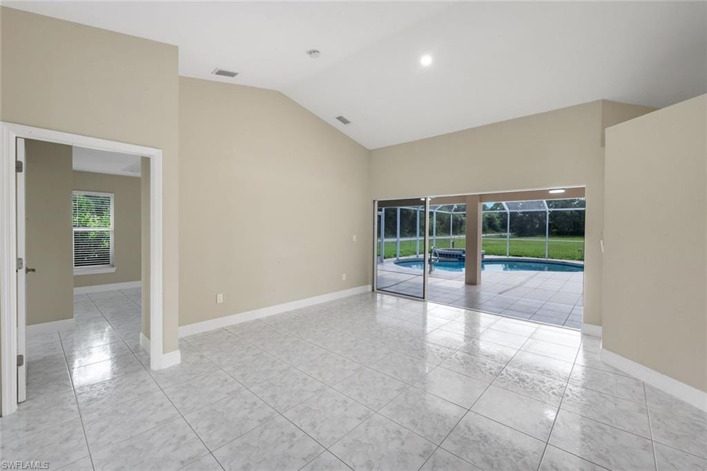 Vaulted ceilings enhance this room featuring light-toned tile flooring and recessed lighting