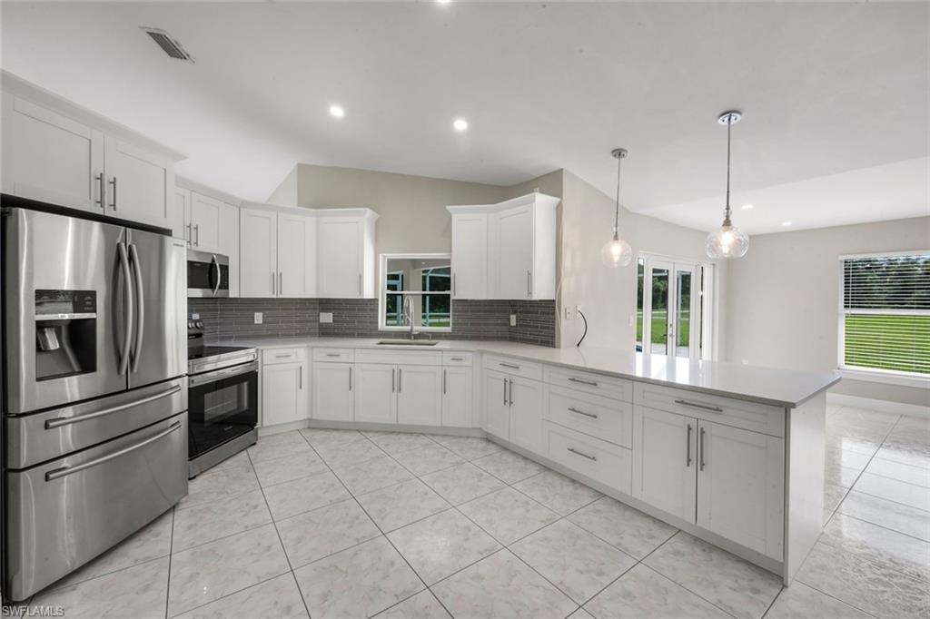 Kitchen featuring white cabinetry, stainless steel appliances, a tile backsplash, and a large island with pendant lighting