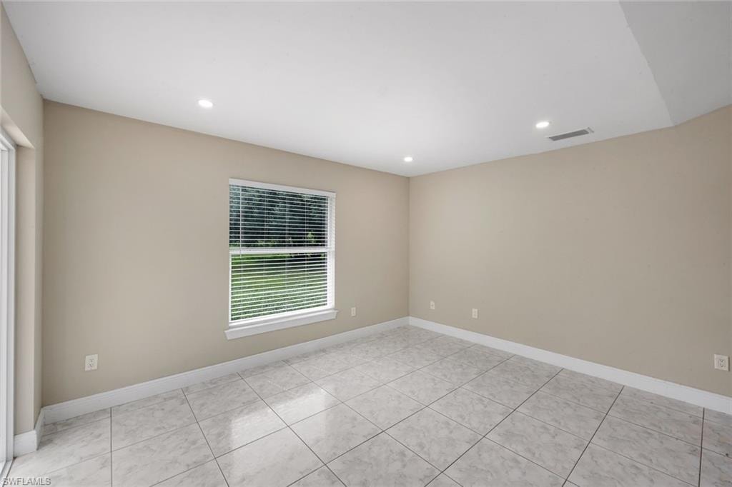Spacious room featuring tile flooring, neutral wall tones, recessed lighting, and a large window with blinds