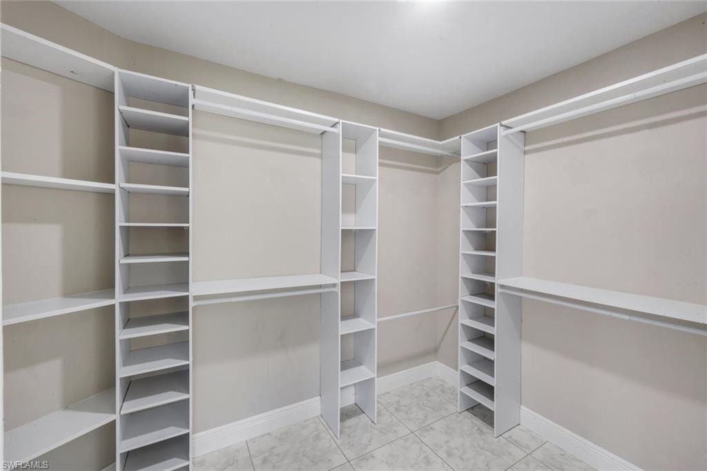 Custom closet system with multiple shelving units, hanging rods, and tiled flooring