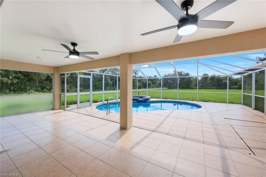 Screened lanai featuring a swimming pool, hot tub, tile flooring, and two ceiling fans