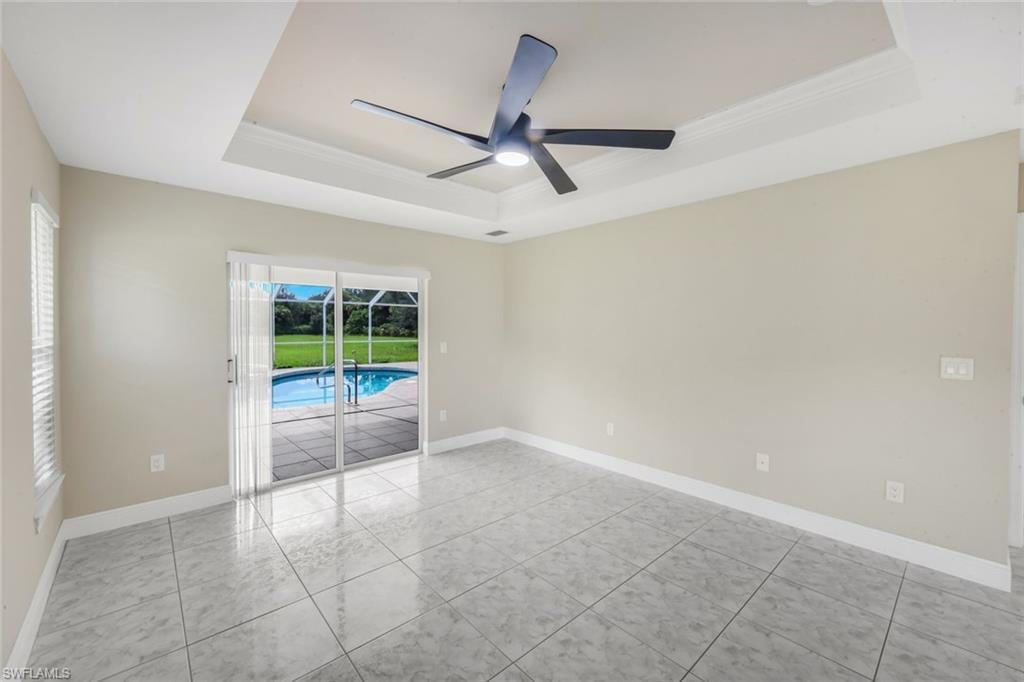 Recessed tray ceiling with a ceiling fan, sliding glass doors, pool access, and tiled flooring