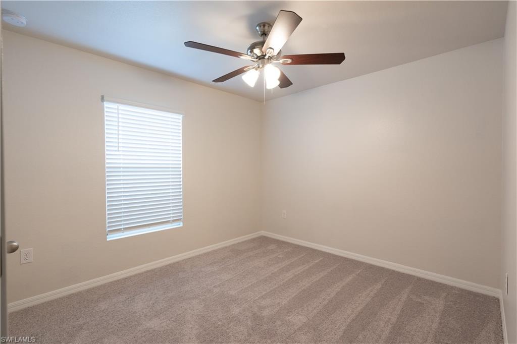 Neutral wall paint with carpet flooring, a ceiling fan with integrated lighting, and a single window with blinds