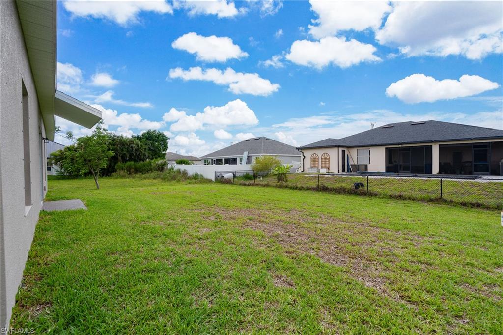 Expansive green space with defined property line, bordered by a white privacy wall
