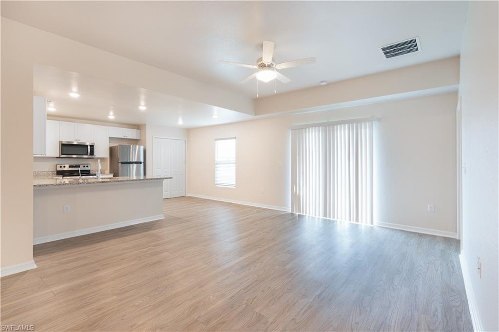 Open concept living area featuring wood-finish flooring, a ceiling fan, and sliding glass doors
