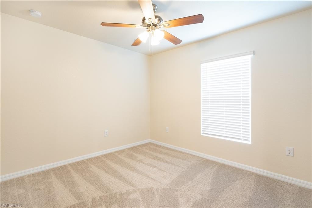 Bright corner bedroom with neutral wall finishes, wood-finish flooring, and large window with plantation shutters