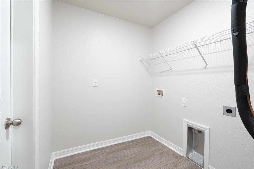Utility space featuring a wire shelving unit and wood-finish flooring