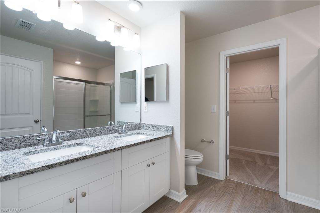 Dual vanity with undermount sinks, granite-finish countertop, and wood-finish flooring