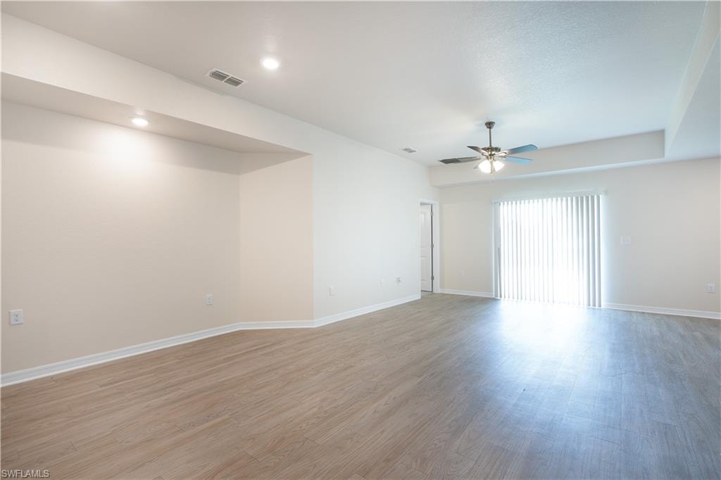 Recessed lighting, wood-finish flooring, ceiling fan, sliding glass door, and tray ceiling