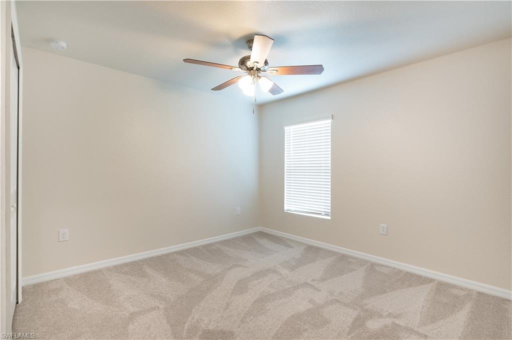 Wall-to-wall carpeting with a neutral tone, ceiling fan with integrated lighting, and a single window with horizontal blinds