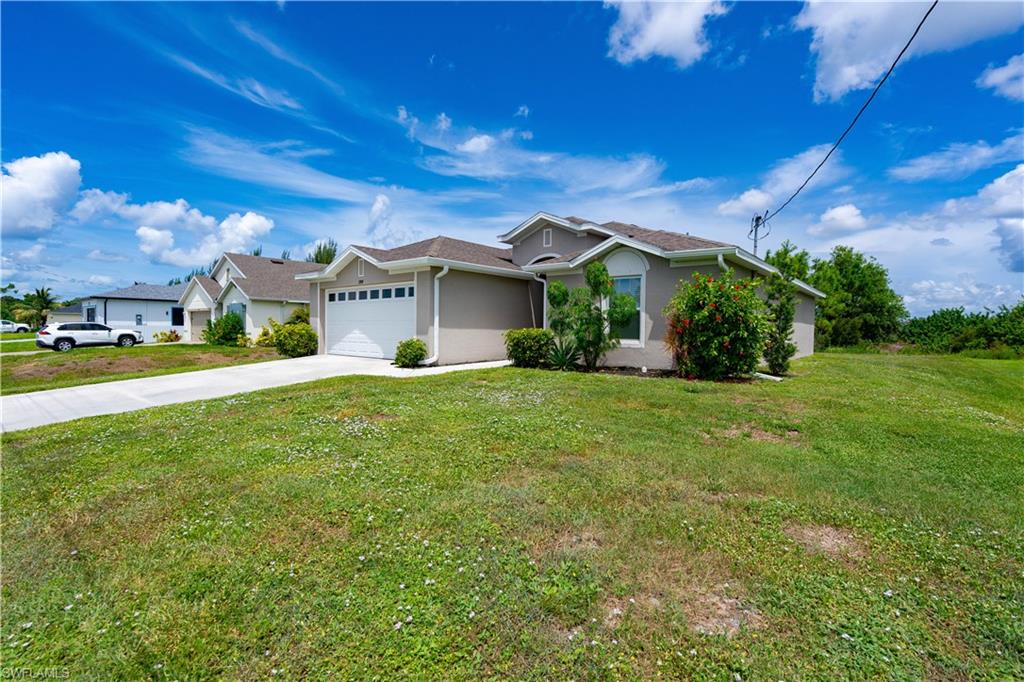 Contemporary single-story exterior with an attached two-car garage, concrete driveway, and established landscape plantings